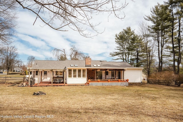 rear view of house with fence, a yard, a sunroom, a chimney, and a deck