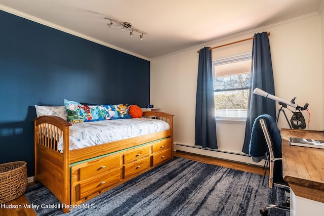 bedroom featuring a baseboard radiator, ornamental molding, rail lighting, and wood finished floors