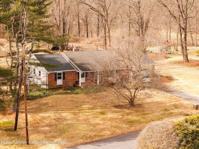 view of front facade with brick siding, a chimney, and a shingled roof