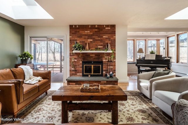 living area with a fireplace, wood finished floors, a skylight, and a healthy amount of sunlight