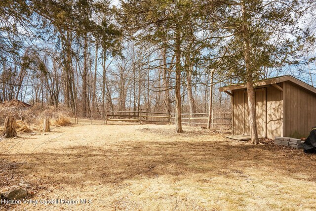 view of yard featuring an outbuilding, a storage unit, and fence