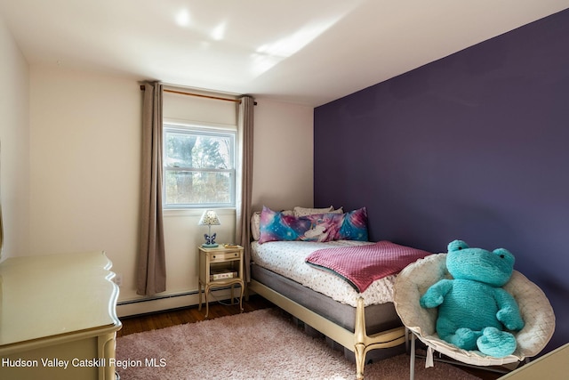 bedroom featuring a baseboard heating unit and wood finished floors