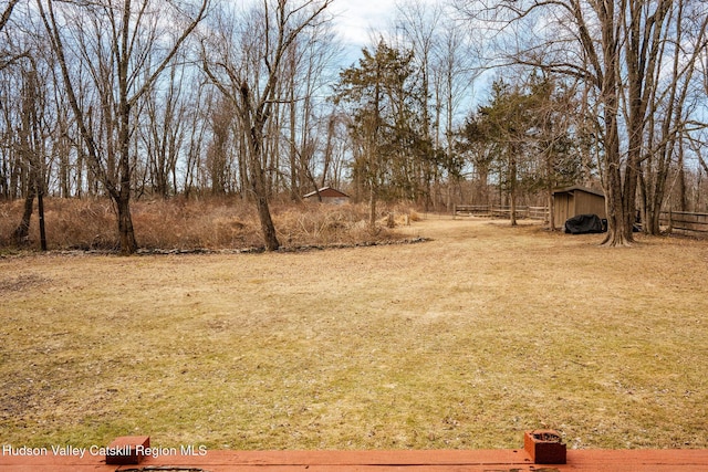 view of yard with an outdoor structure, a shed, and fence