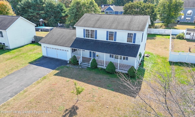 view of front of home with covered porch, a garage, and a front lawn