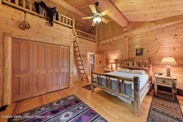 bedroom featuring light wood-type flooring, vaulted ceiling with beams, ceiling fan, and wood ceiling