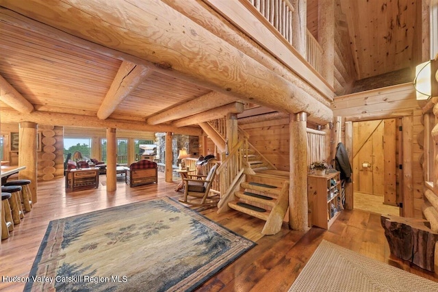 interior space featuring log walls, hardwood / wood-style floors, wooden ceiling, and beam ceiling