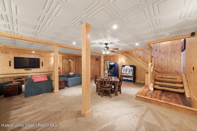 interior space featuring carpet flooring, ceiling fan, and wood walls