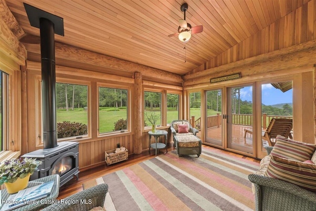 sunroom / solarium with a wood stove, ceiling fan, lofted ceiling, and wood ceiling