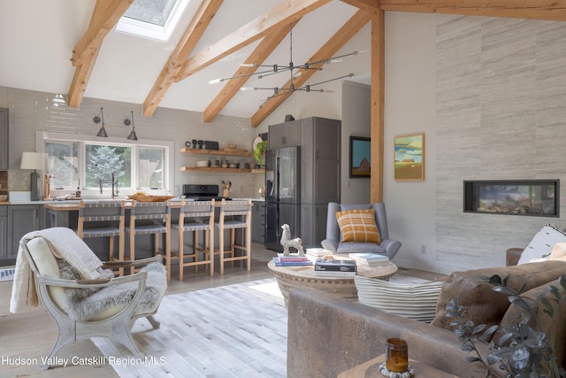 46 Rose Ln, Woodstock, NY 12409 - living area featuring a skylight, high vaulted ceiling, beamed ceiling, a tiled fireplace, and light wood-style flooring