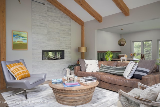 46 Rose Ln, Woodstock, NY 12409 - living room featuring wood finished floors, beamed ceiling, a fireplace, high vaulted ceiling, and an accent wall