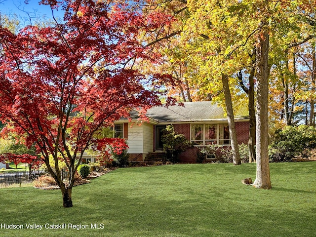 view of front of house with brick siding, fence, and a front yard