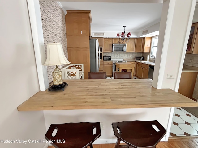 kitchen featuring stainless steel appliances, hanging light fixtures, light countertops, and decorative backsplash