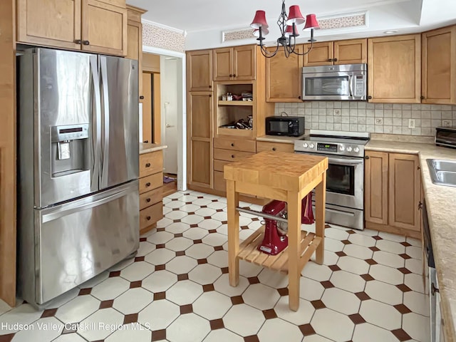 kitchen featuring a notable chandelier, tasteful backsplash, light countertops, appliances with stainless steel finishes, and ornamental molding