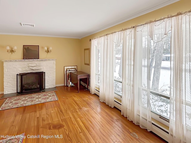 unfurnished living room featuring crown molding, visible vents, a fireplace, and wood finished floors