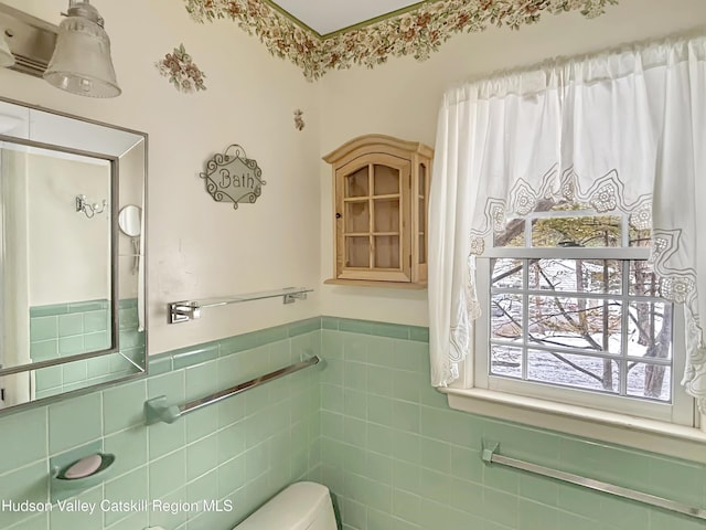 bathroom with toilet, wainscoting, and tile walls