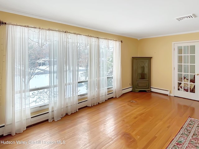 doorway to outside featuring a healthy amount of sunlight, a baseboard radiator, visible vents, and wood finished floors