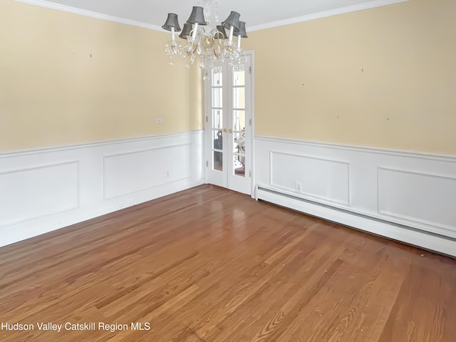 unfurnished dining area with a baseboard radiator, wainscoting, crown molding, and wood finished floors