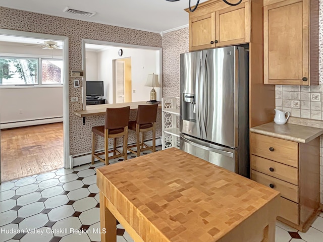 kitchen with crown molding, a baseboard radiator, light countertops, stainless steel fridge with ice dispenser, and wallpapered walls