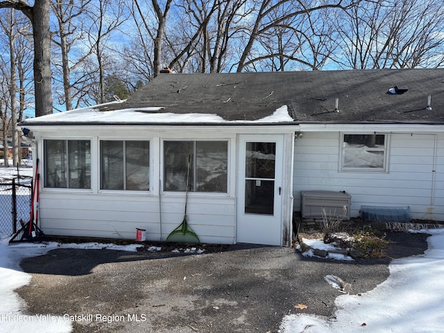 exterior space with a shingled roof and a sunroom