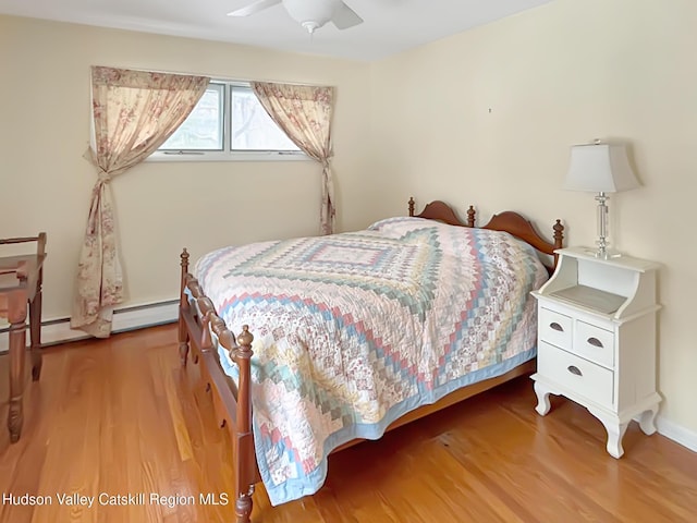 bedroom featuring a baseboard radiator, ceiling fan, and wood finished floors