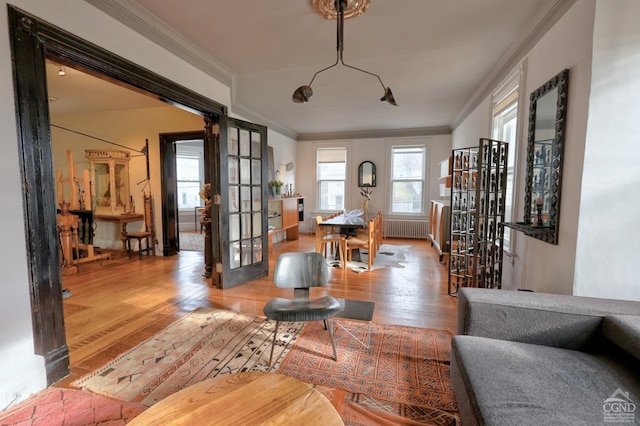 living room with radiator heating unit, wood finished floors, ornamental molding, french doors, and baseboards
