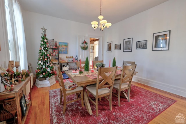 dining area with a chandelier, light wood-style flooring, and baseboards