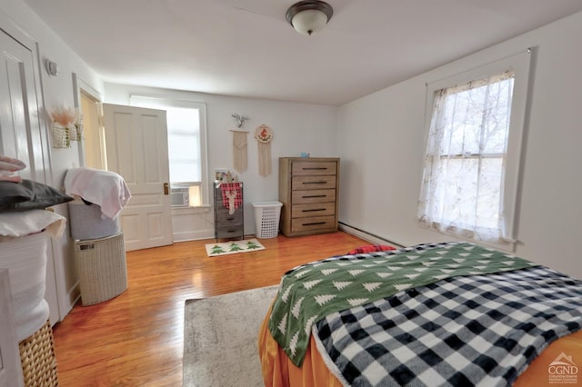 bedroom featuring light wood-style flooring and a baseboard heating unit