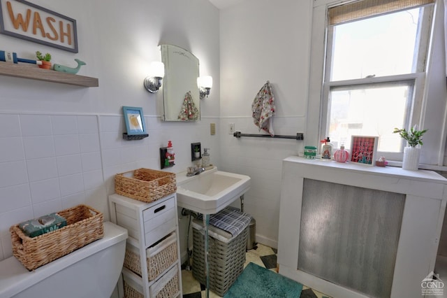 bathroom with tile walls, toilet, and a wainscoted wall