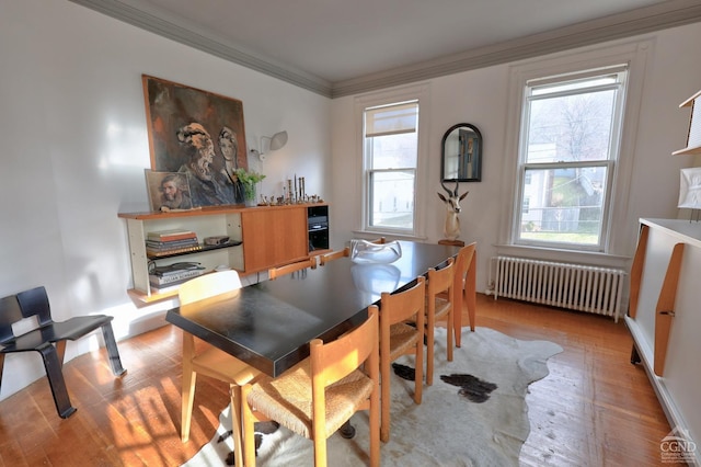 dining area featuring radiator, light wood-type flooring, and crown molding