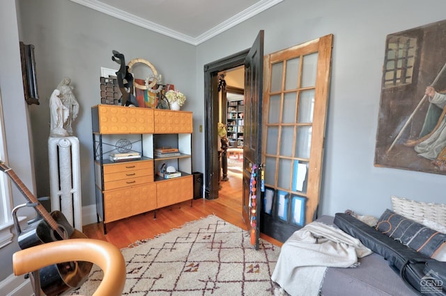home office featuring light wood-type flooring, radiator, and crown molding