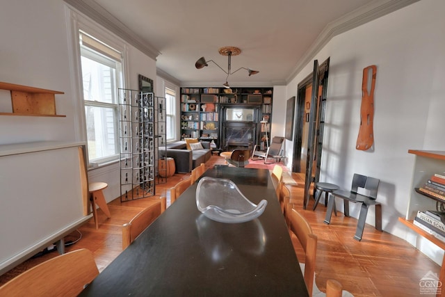 dining area featuring crown molding, healthy amount of natural light, wood finished floors, built in features, and a desk