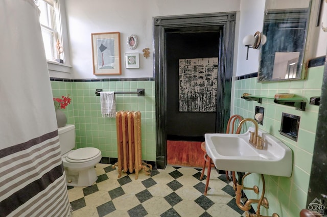 bathroom with tile walls, radiator, tile patterned floors, wainscoting, and toilet