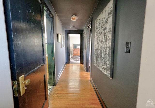 corridor with light wood-style flooring and baseboards