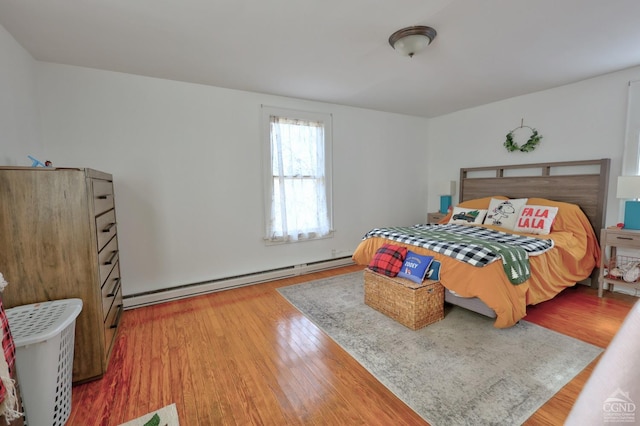 bedroom with baseboard heating and wood finished floors