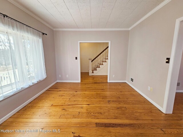 empty room with ornamental molding and light wood-type flooring