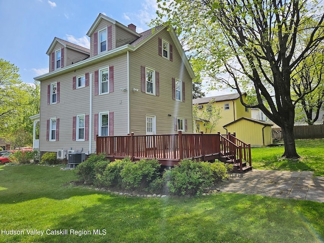 rear view of property featuring a yard, a deck, and central air condition unit