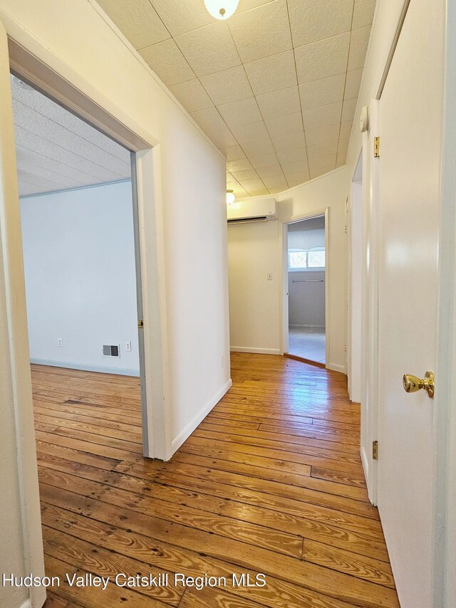 corridor featuring hardwood / wood-style flooring and a wall mounted AC