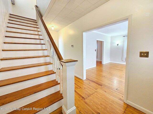 stairway with hardwood / wood-style floors and ornamental molding