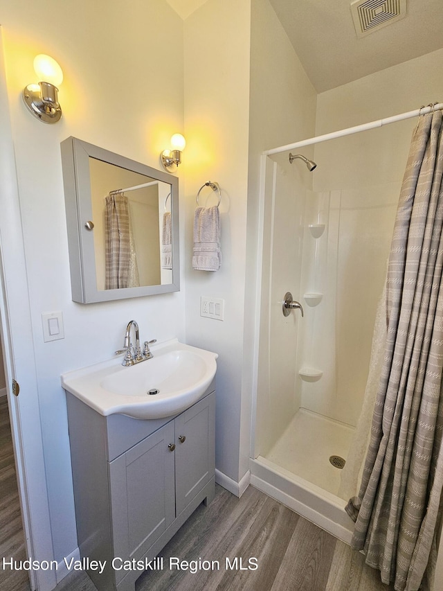 bathroom with vanity, hardwood / wood-style flooring, and walk in shower