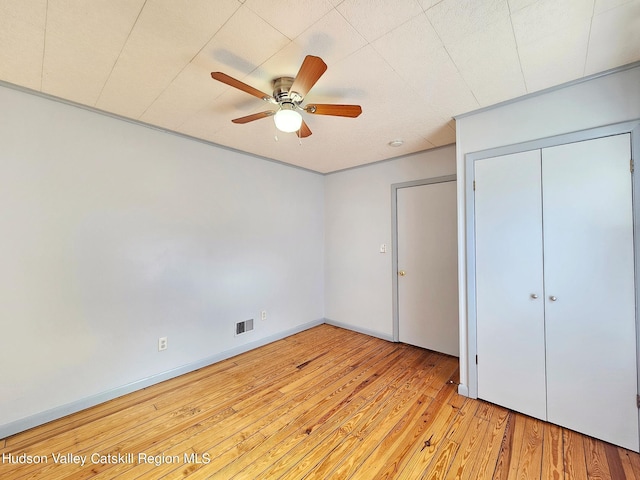 unfurnished bedroom with ceiling fan, light wood-type flooring, and a closet