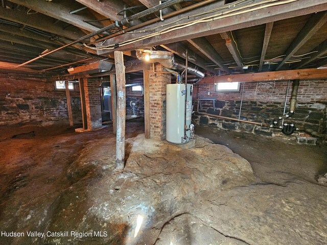 basement featuring gas water heater and brick wall