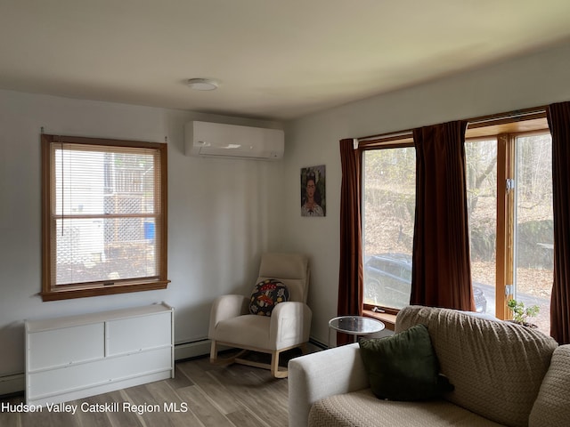 sitting room with wood finished floors and a wall unit AC