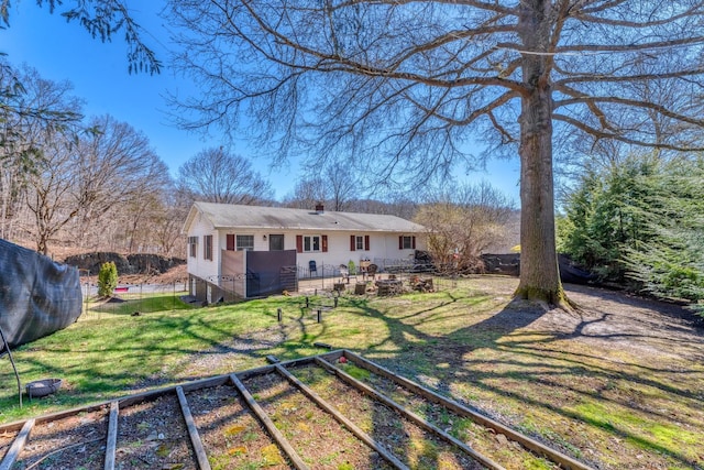 back of house with a lawn and a vegetable garden