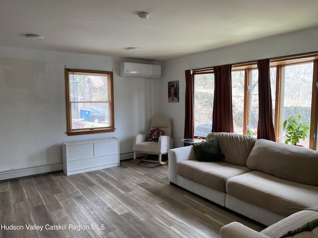living room featuring plenty of natural light, a baseboard heating unit, a wall unit AC, and wood finished floors