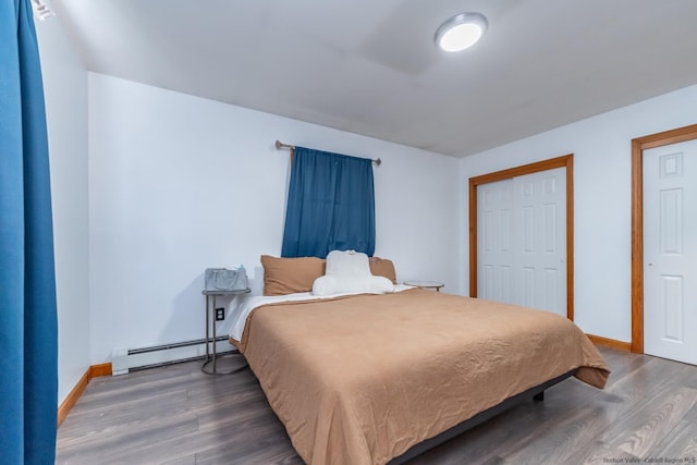 bedroom with wood finished floors, baseboards, and a baseboard heating unit