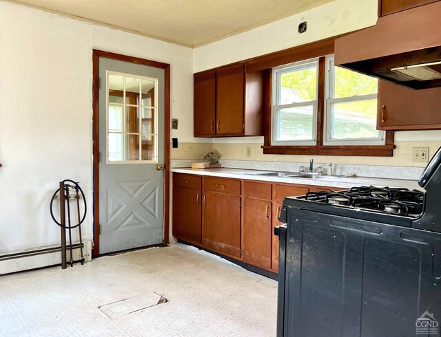 kitchen featuring black range with gas stovetop, extractor fan, light countertops, brown cabinets, and light flooring