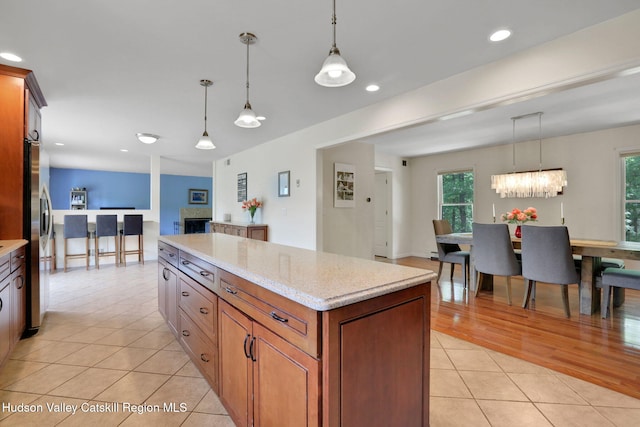 14 Glenerie Ln, Saugerties, NY 12477 - kitchen with light tile patterned flooring, a kitchen island, stainless steel refrigerator with ice dispenser, brown cabinets, and pendant lighting