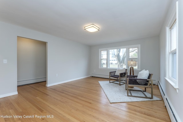 living area with light hardwood / wood-style floors and baseboard heating