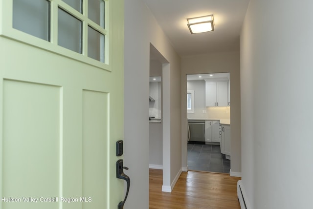 corridor featuring a baseboard heating unit and light wood-type flooring