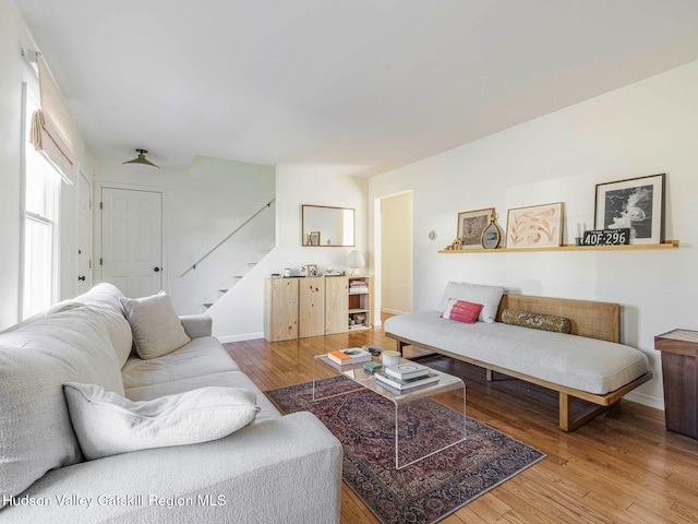 living area with light wood-style flooring, baseboards, and stairs